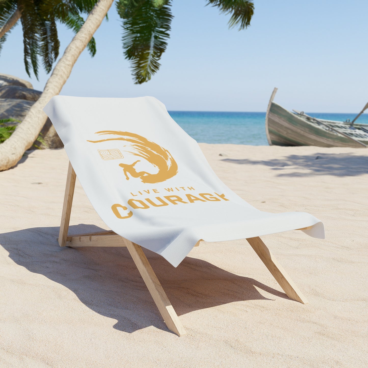 a white 30 by 60 inch beach towel with a graphic of a surfing girl inside an arcing wave in gold on a wooden beach chair in a tropical scene. the Live With Courage®️logo underneath.