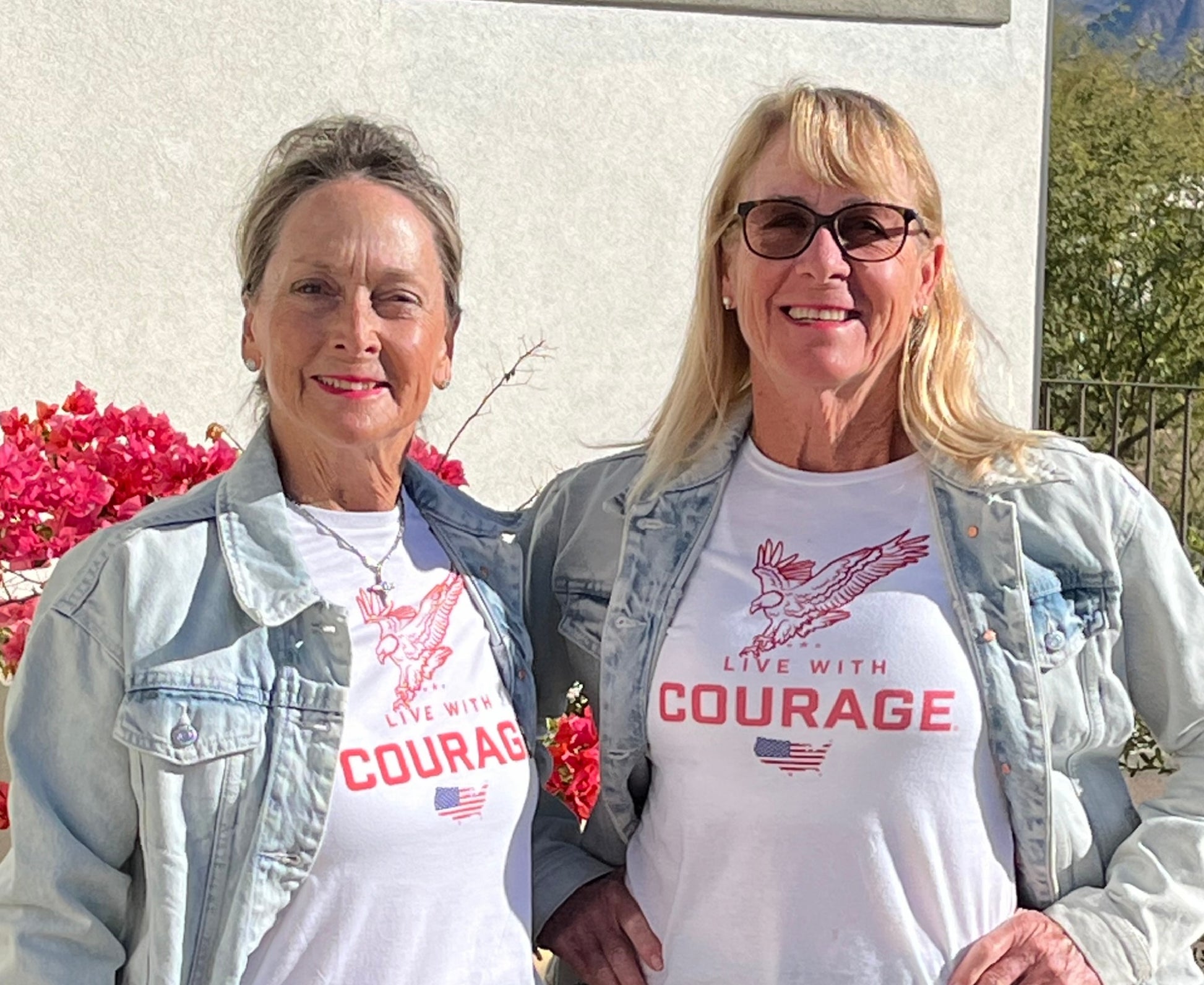 Two women wearing white tee shirts with an American eagle and flag and the words Live With Courage.