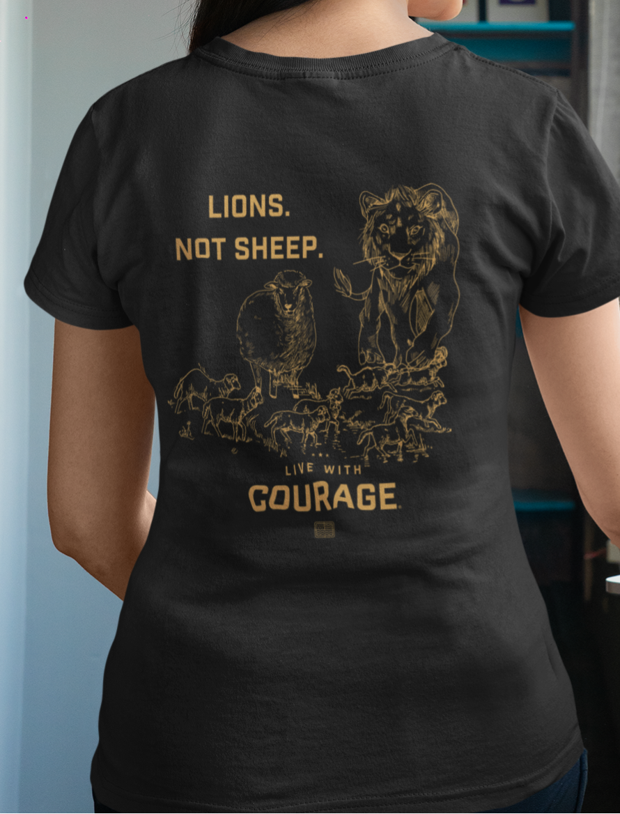 A woman wearing a black crew neck t-shirt with the text 'LIONS. NOT SHEEP above a graphic of a lion standing over sheep and the words Live With Courage.