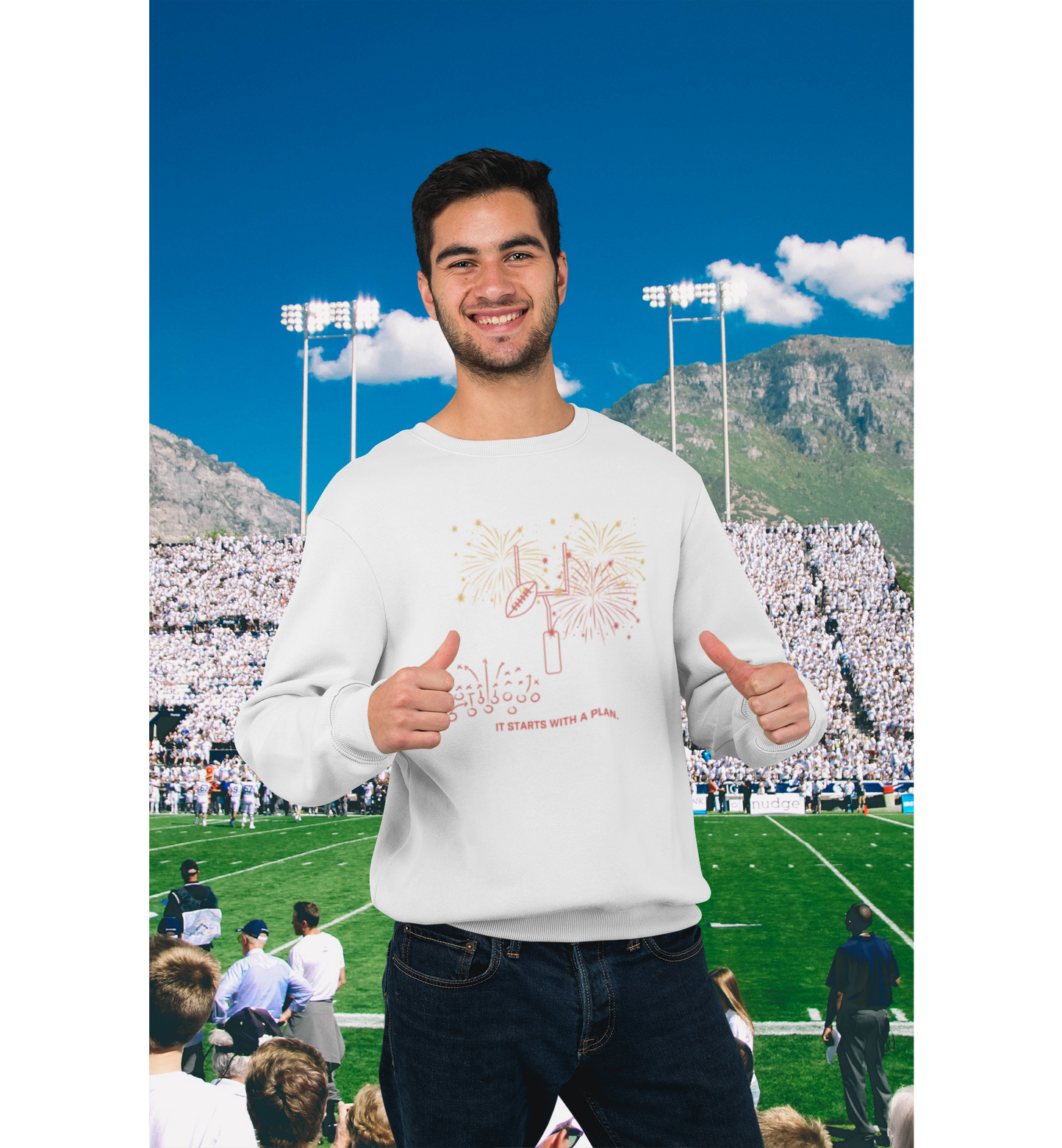 A person wearing a white crewneck sweatshirt with a football-themed graphic, standing in front of a generated backdrop of a sports stadium with a crowd and mountains.