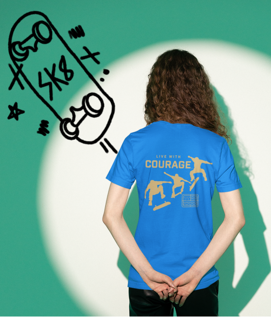 A woman in a blue tee shirt with a graphic design of skateboarders and the words Live With Courage.
