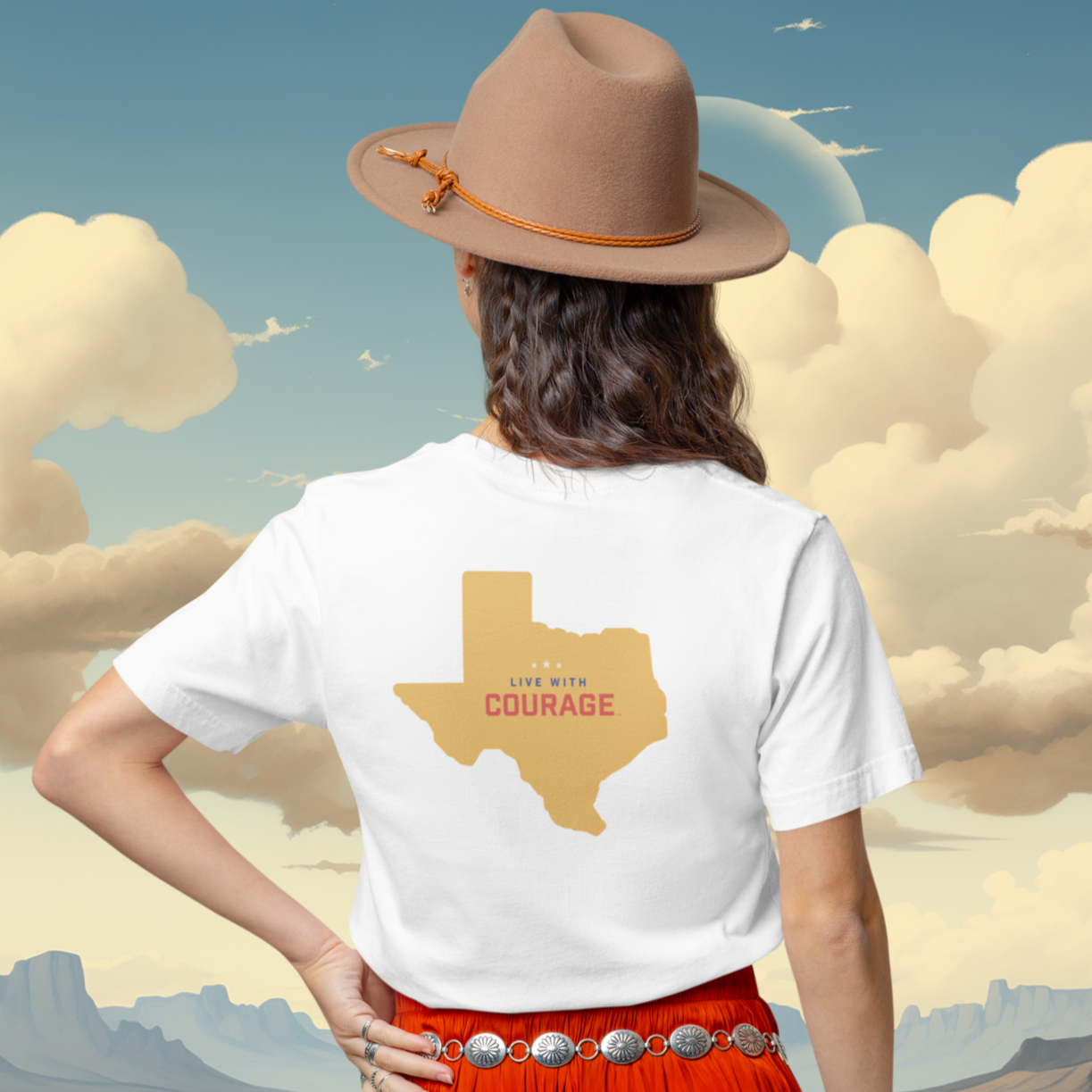 A person wearing a white short-sleeve t-shirt with a silhouette of Texas and the text 'LIVE WITH COURAGE' on the back, paired with a hat and red pants.