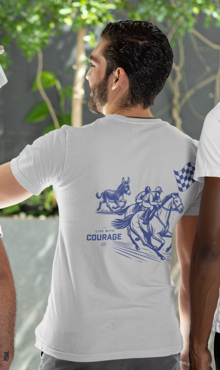 Man wearing a white tee shirt with a picture of a horse race with two horses and a mule racing and the words Live With Courage.