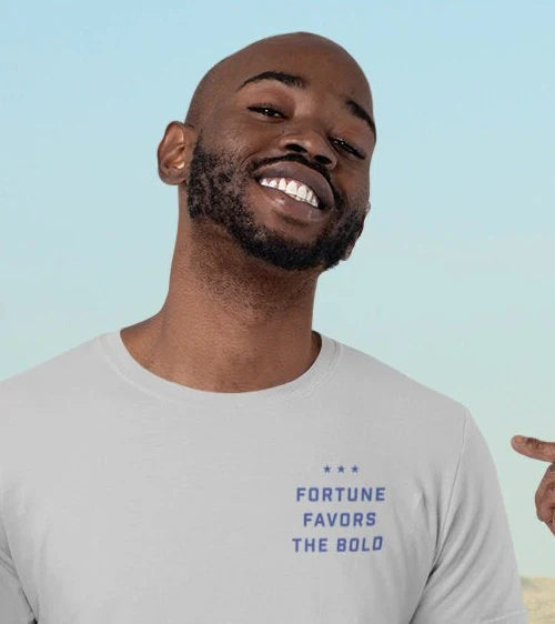 A man smiling and pointing to his white tee shirt with the words Fortune Favors the Bold.
