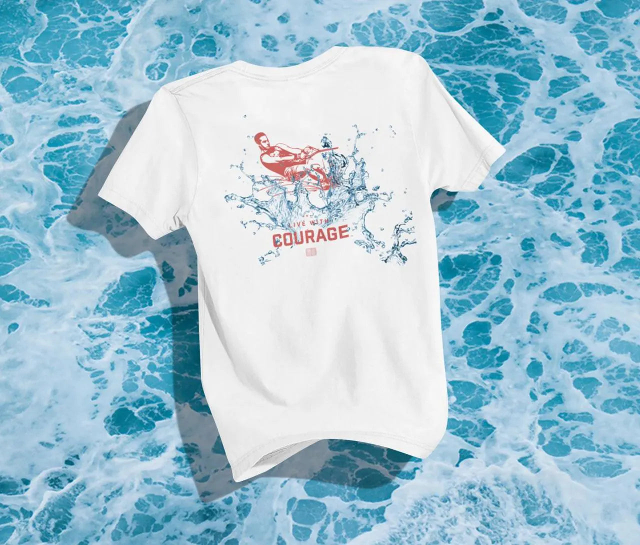 A white unisex short sleeve tee with a graphic of a slalom water skier on the back and the text 'LIVE WITH COURAGE' above the graphic. 