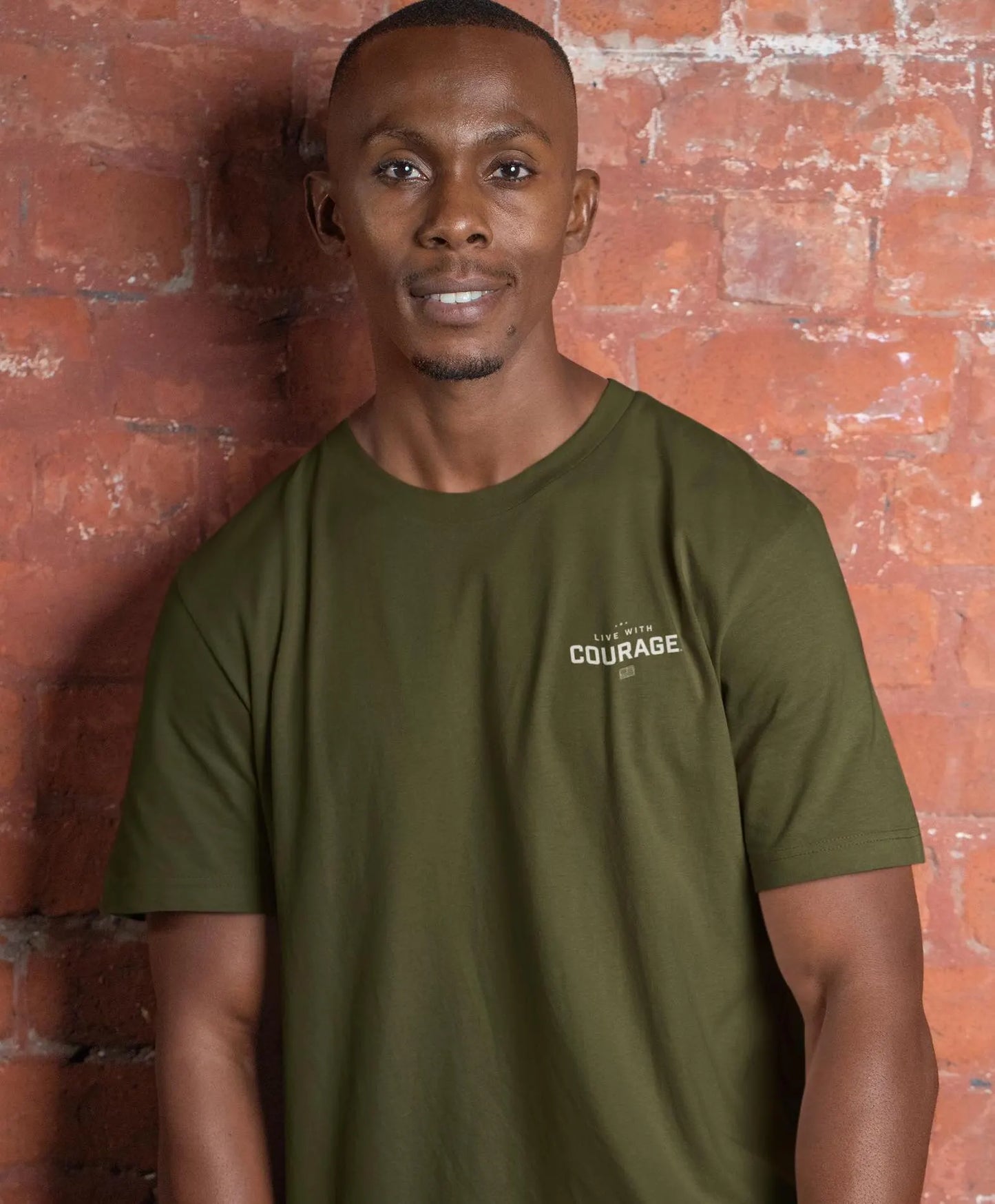 A person wearing a green short-sleeved t-shirt with the text 'LIVE WITH COURAGE' on the front chest area.