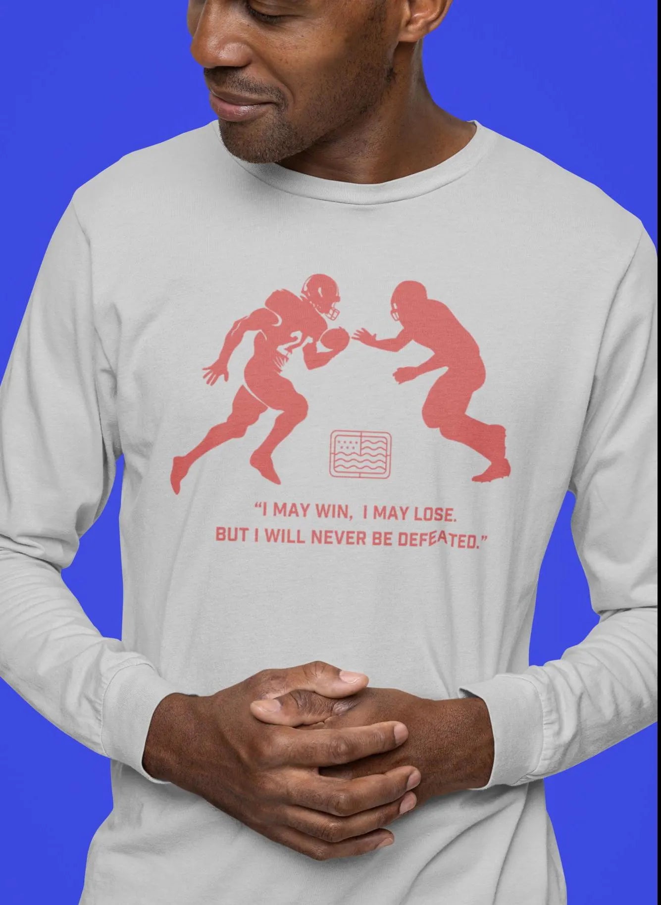 A man wearing a white unisex long sleeve tee with a football theme graphic and quote from Emmitt Smith.
