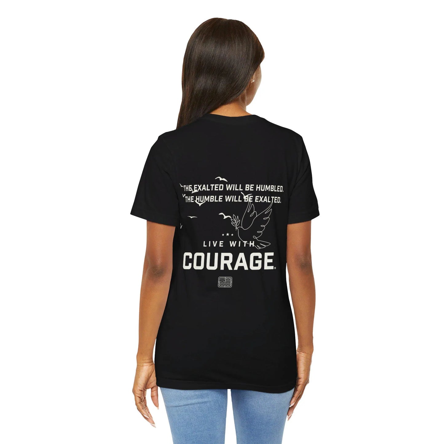 A woman facing away from the camera wears a black crew neck t-shirt with the text The Exalted with be humbled and the humble will be exalted and a design of a dove over the words Live With Courage.