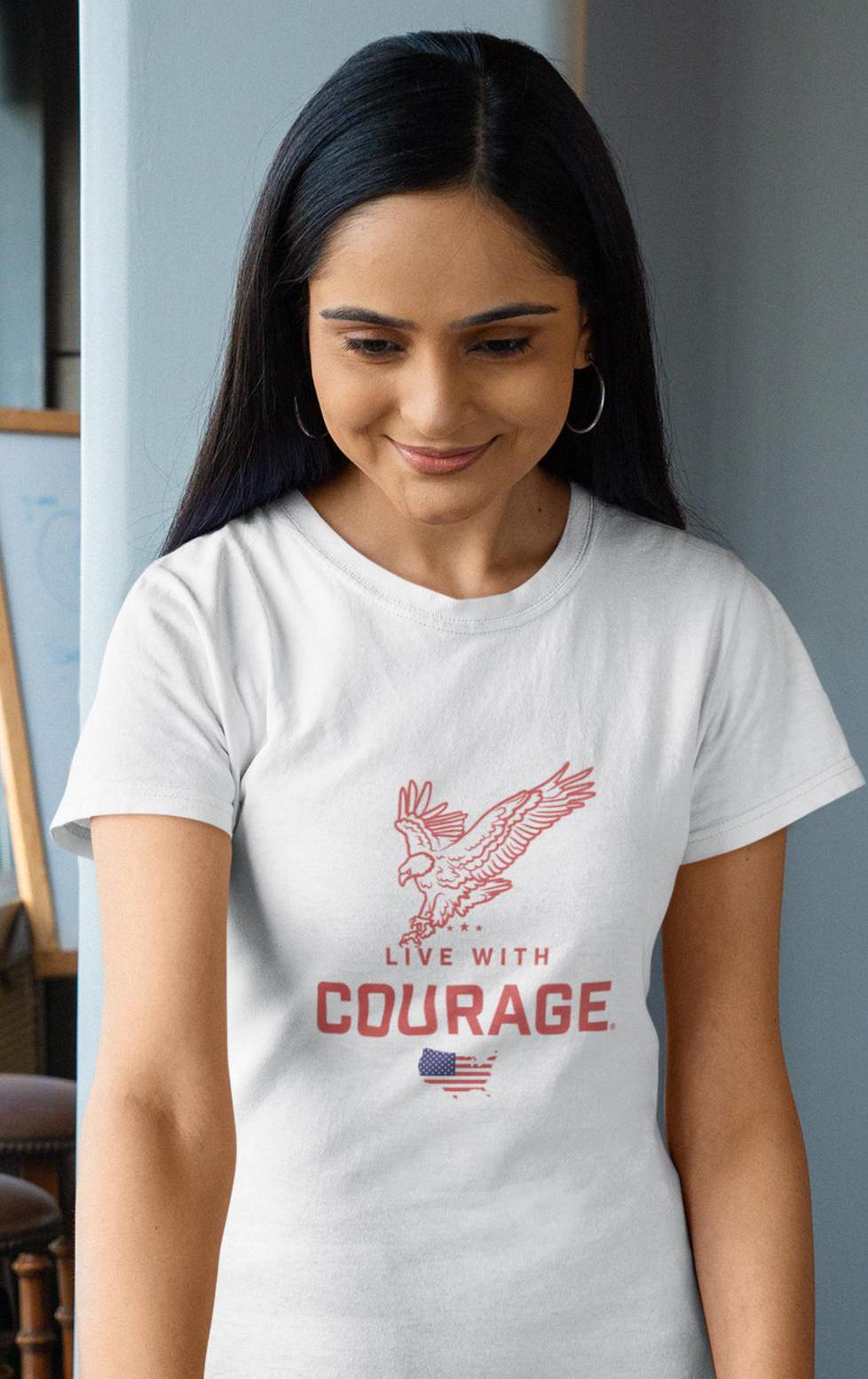 A woman smiling and wearing a white crew neck t-shirt with the text 'Live With Courage' and the image of an American Bald Eagle on the front.
