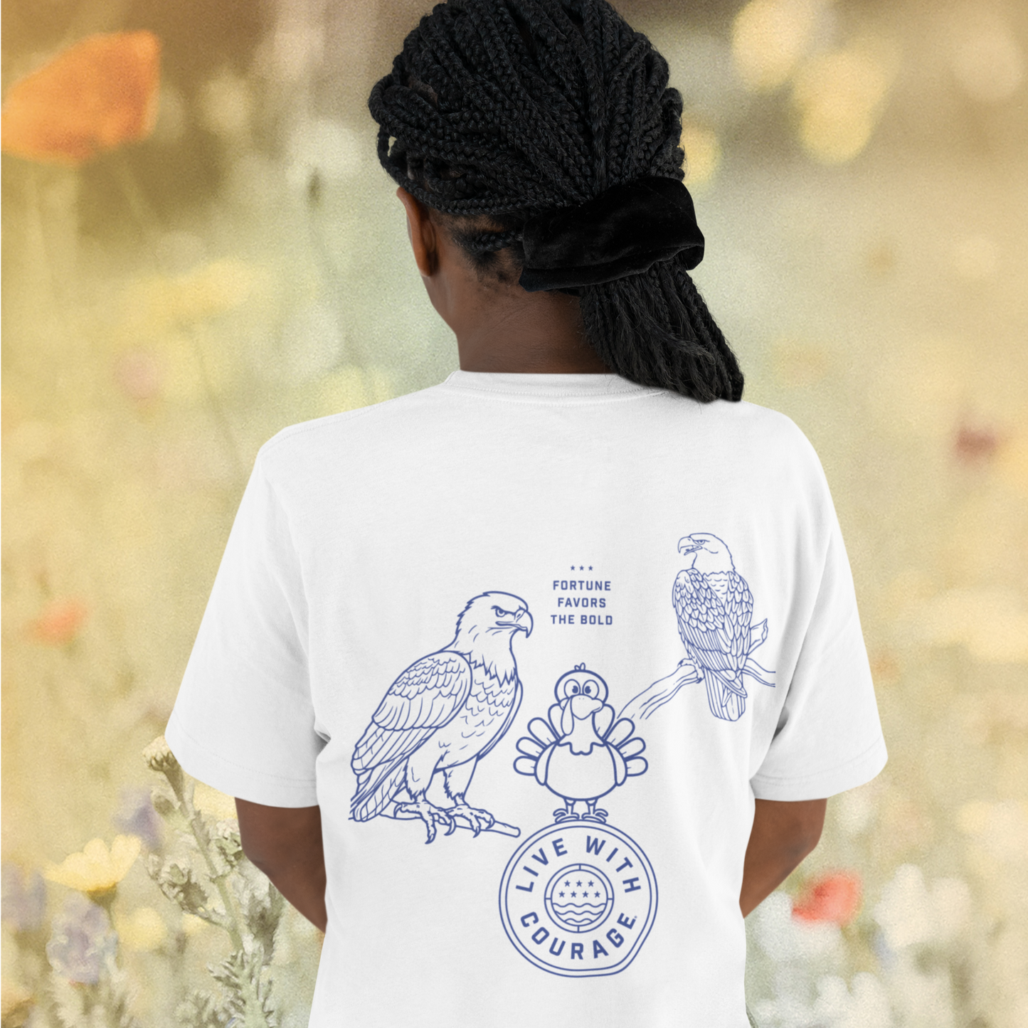Back view of a young girl wearing a white Live With Courage® Thanksgiving t-shirt showcasing a bold design of a turkey between two eagles with the phrase 'Fortune Favors the Bold'.