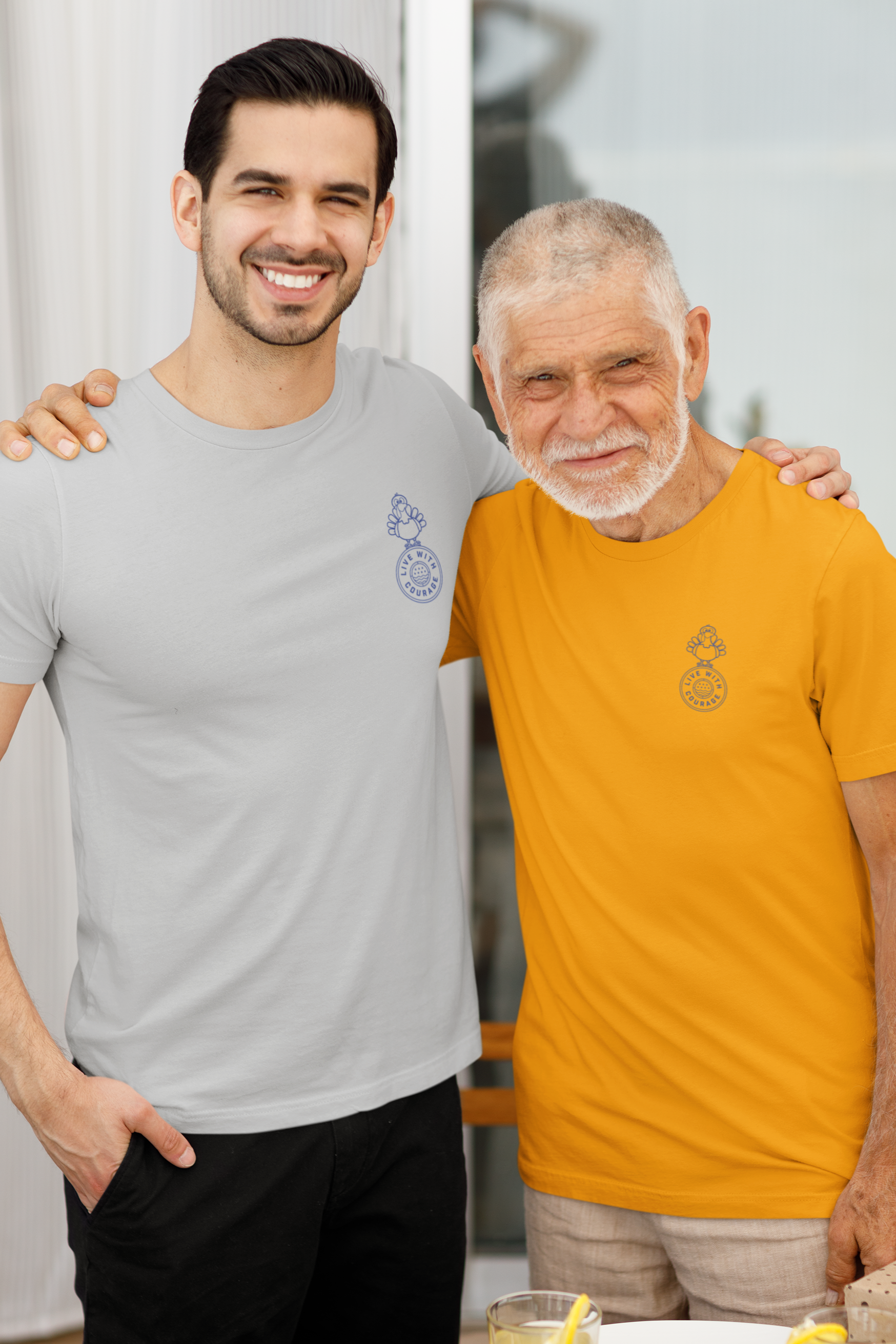 Father and grandfather pose together before a meal, wearing matching Live With Courage® t-shirts with the Thanksgiving turkey emblem on the front.