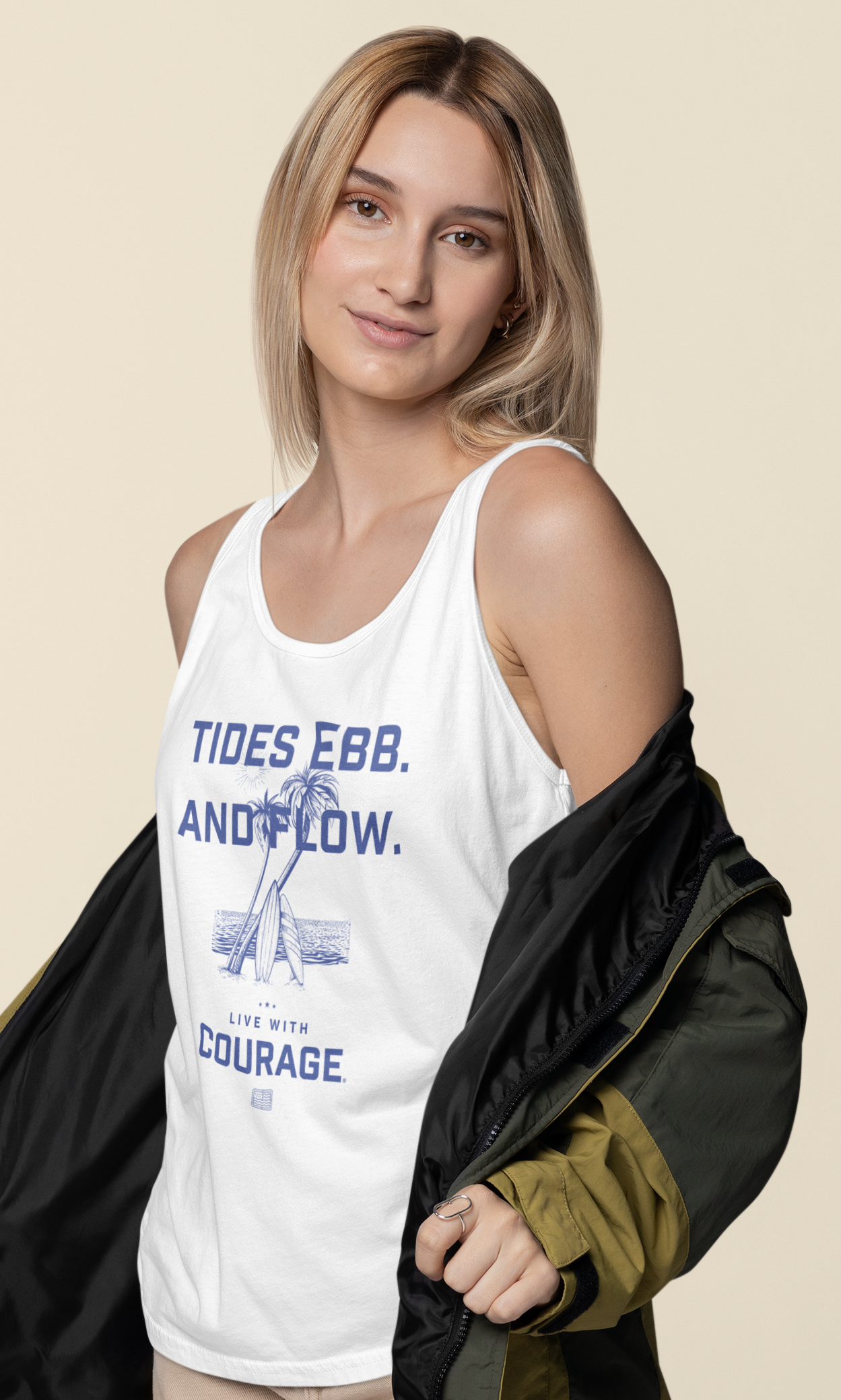 A woman wearing a white tank top with the words Tides Ebb and Flow and Live With Courage and a graphic of an island with palm trees and surfboards.